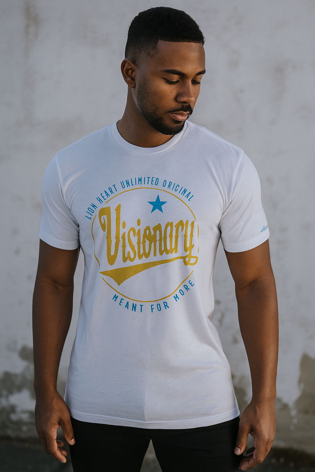 Man wearing a white t-shirt with 'Visionary' printed on it against a gray wall.
